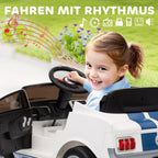 Mergaitė sėdi balto elektrinio automobilio vairuotojo sėdynėje ir laiko vairą