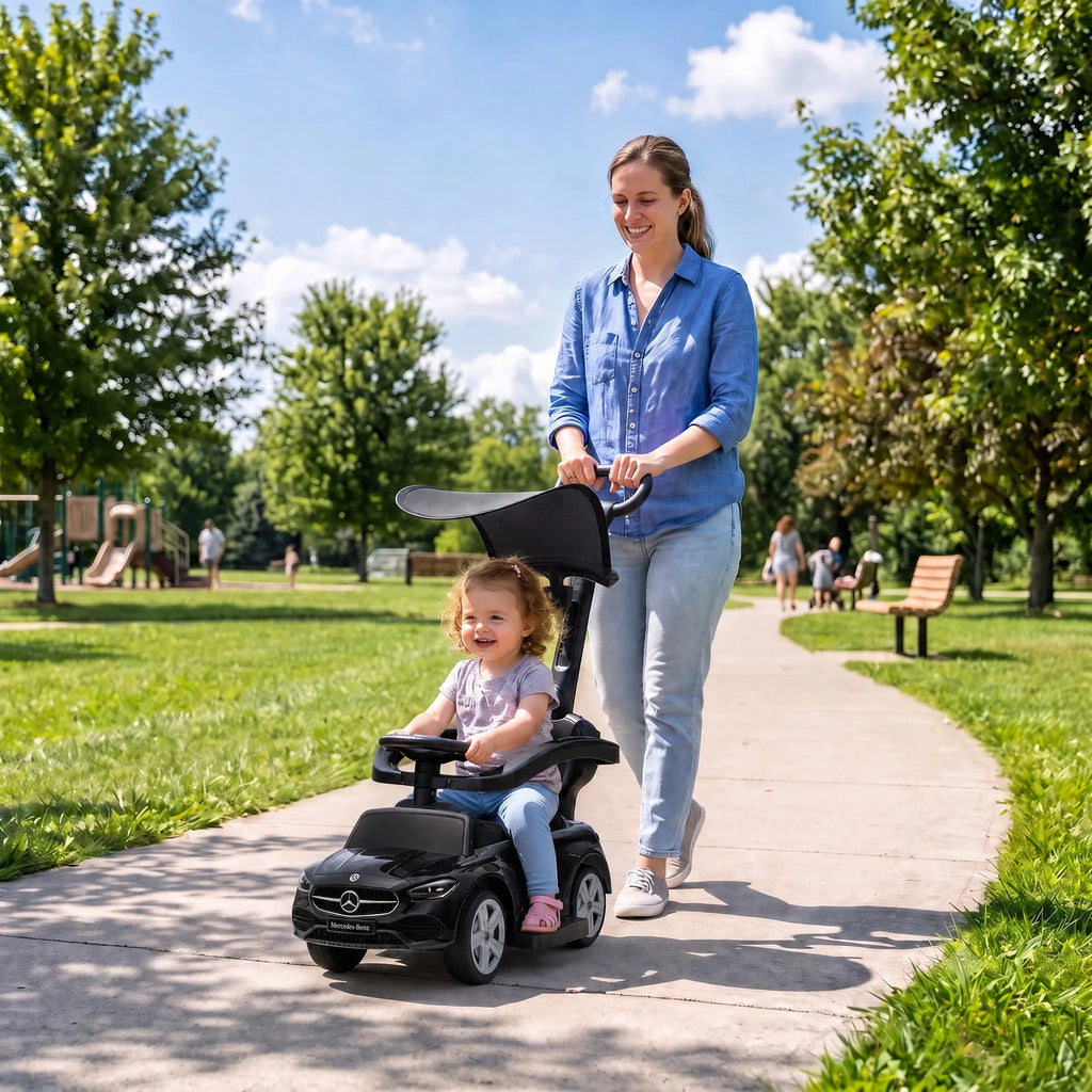 Mama stumia vaiką juodame automobilyje-stumduke parko takeliu