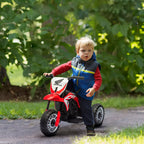 Mažas berniukas stumia raudoną Honda elektrinį motociklą lauke rudens aplinkoje