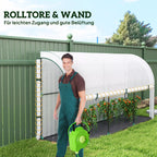 Vyras su žarnos ritinėliu šalia atidaryto šiltnamio su paprikomis