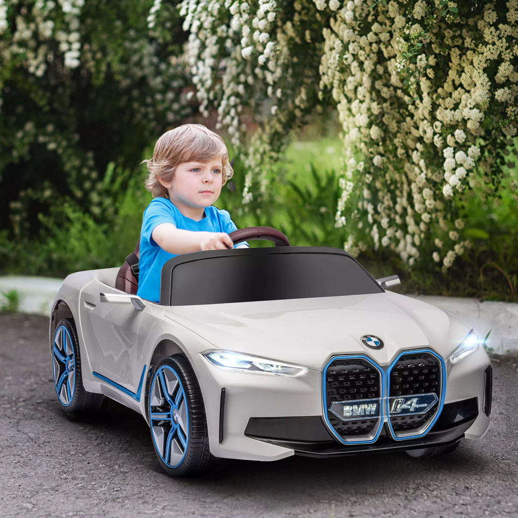Vaikas sėdi baltame elektromobilyje lauke