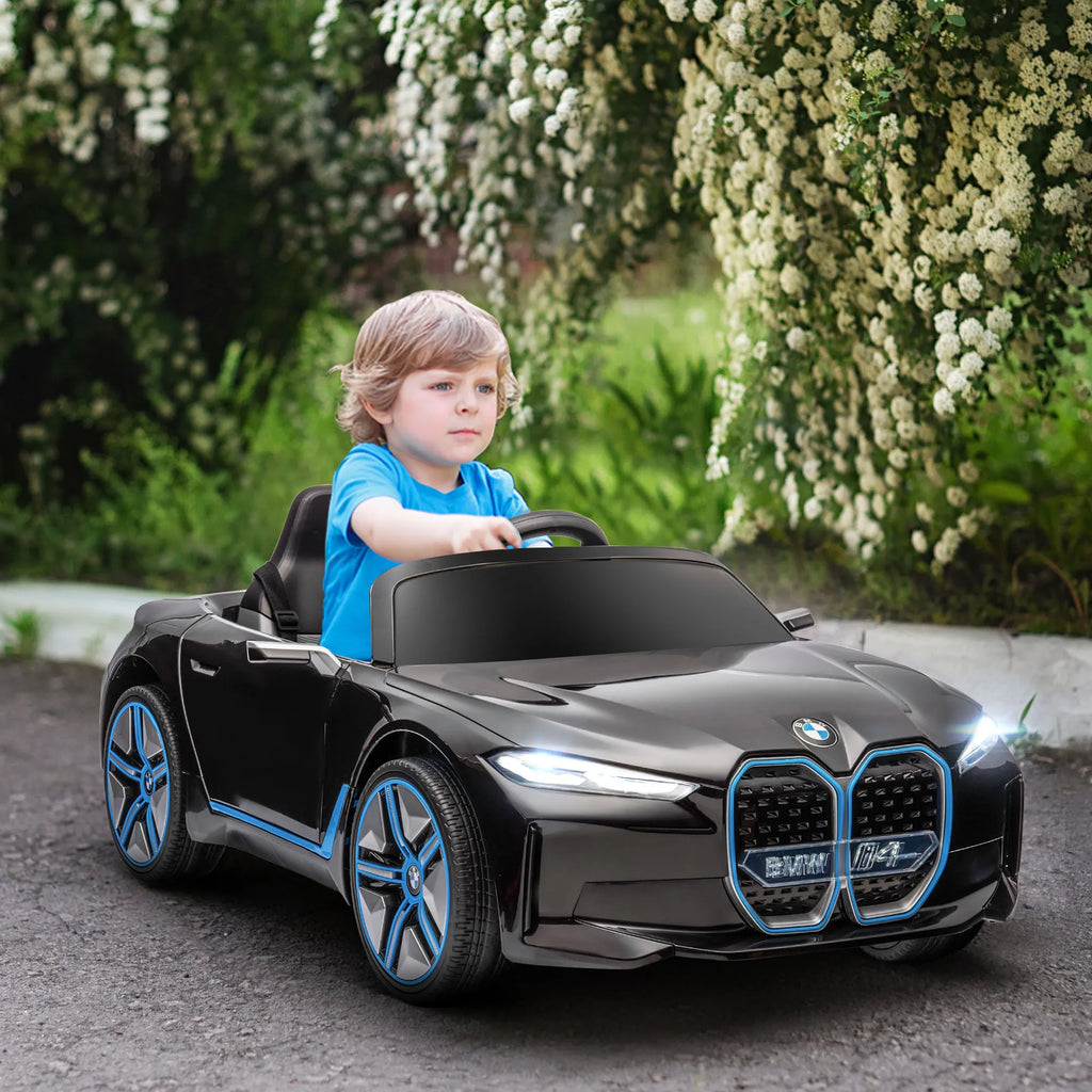 Vaikas sėdi juodame elektromobilyje lauke