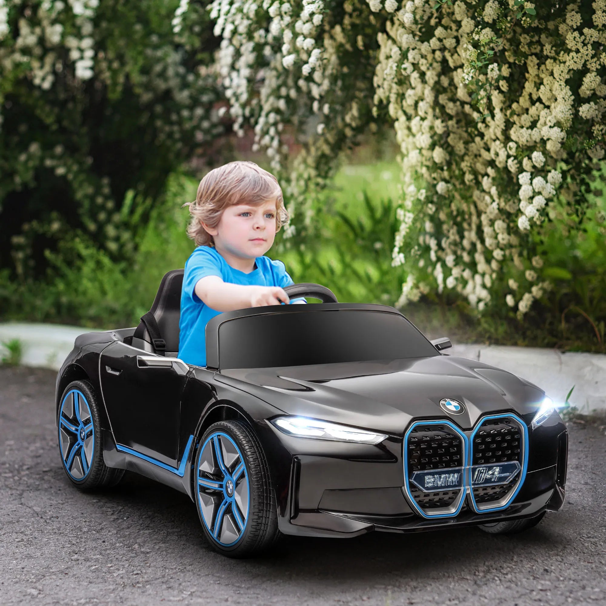 Vaikas sėdi juodame elektromobilyje lauke