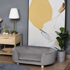 Šviesiai pilka gyvūnų sofa prie staliuko su lempa