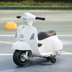 Ant kelio pastatytas vaikiškas elektromotoroleris Vespa šalia kūgio