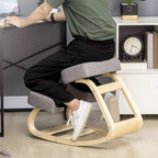 Žmogus klūpi ant ergonominės kėdės prie stalo