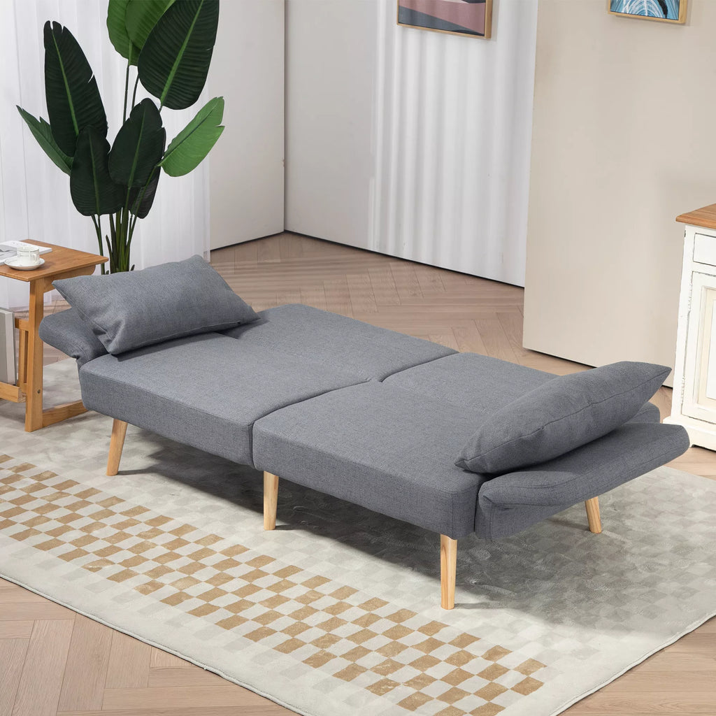 Pilka miegamoji sofa išskleista kaip lova kambaryje