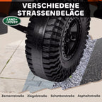 Moteris laiko nuotolinio valdymo pultą šalia oranžinio Land Rover Defender elektromobilio