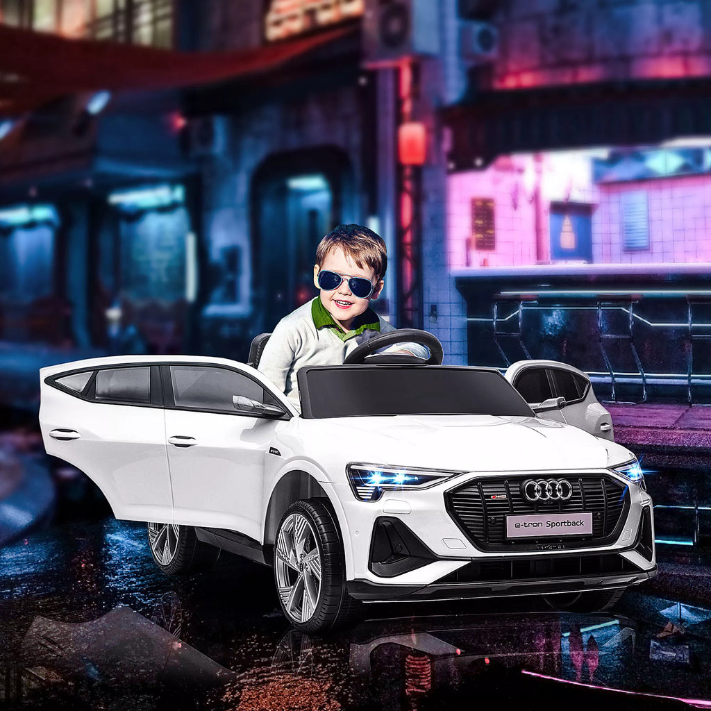 Berniukas sėdi baltame vaikų Audi automobilyje naktiniame fone