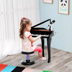Mergaitė sėdi prie juodo vaikiško pianino su mikrofonu