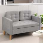 Sofa svetainėje šalia baltos pufo kėdutės ir knygų su augalu fone