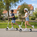 Du vaikai su šalmais važiuoja baltais elektriniais paspirtukais parke