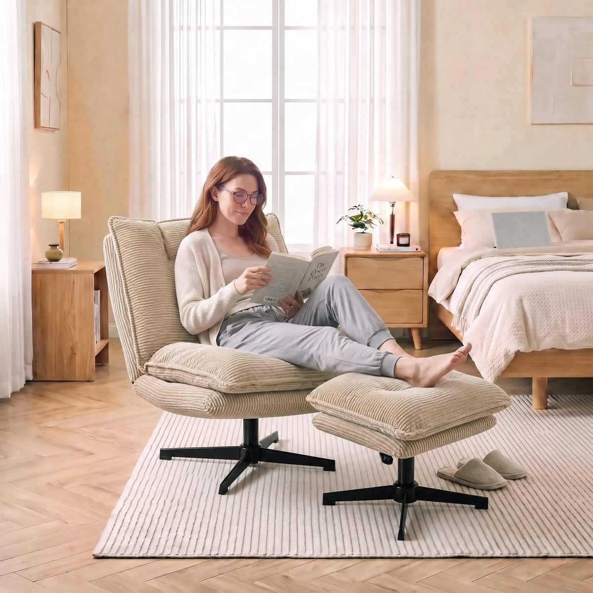 Miegamajame įrengtas smėlio spalvos fotelis su pufu, moteris skaito knygą