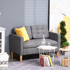 Pilka aksominė dviejų vietų sofa su geltona pagalvėle kambaryje