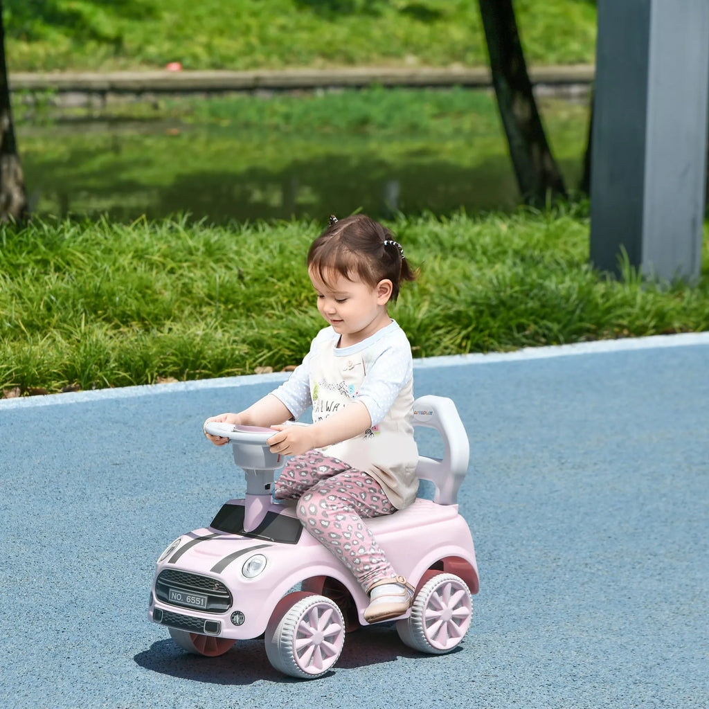 Mergaitė važiuoja rožiniu stumiamuoju automobiliu lauke
