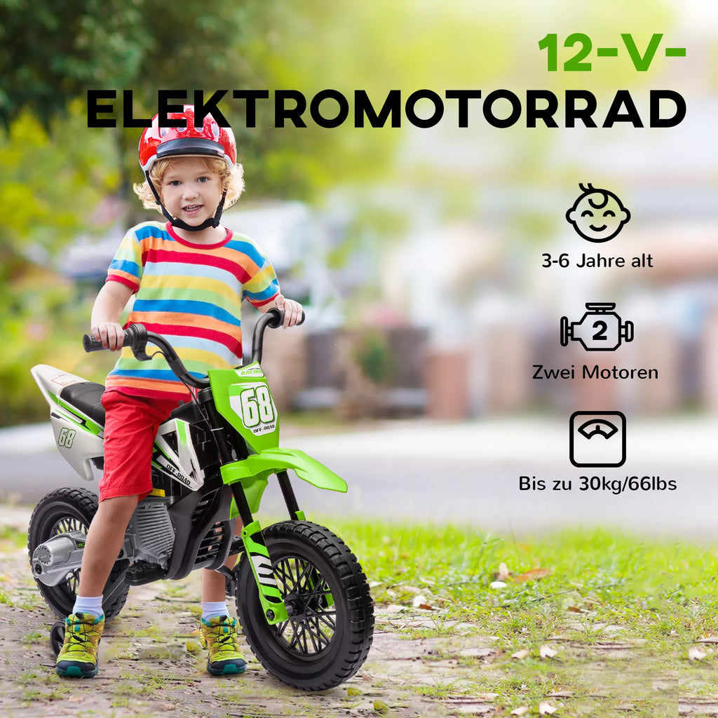 Berniukas su šalmu sėdi ant žalio elektrinio vaikų motociklo pievoje