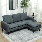 Svetainėje prie lango pastatyta pilka kampinė sofa su pufu ant šviesaus kilimo