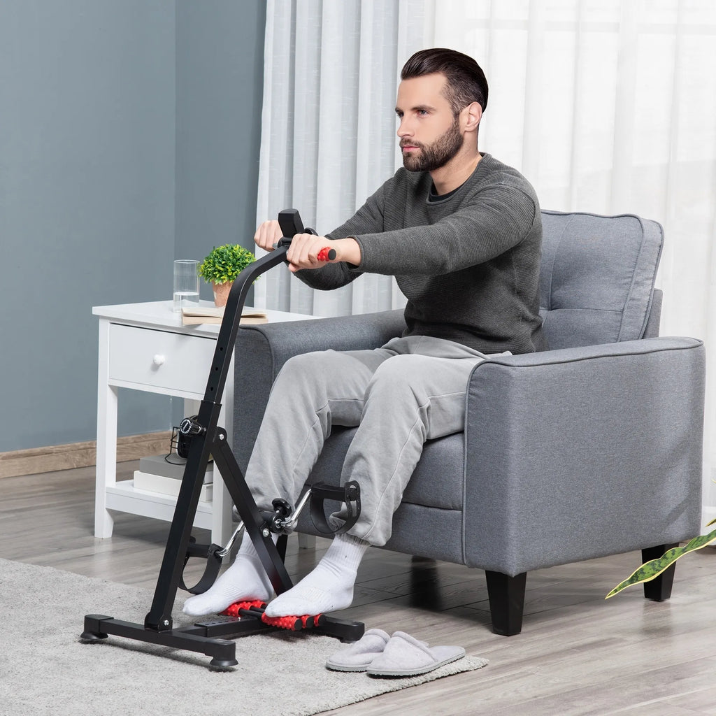 Vyras fotelyje mina treniruoklio pedalus šalia naktinio staliuko