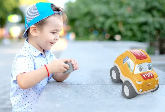 Vaikas lauke žaidžia nuotoliniu būdu valdomu žaisliniu automobiliuku