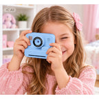 Mergaitė fotografuoja mėlynu vaikišku fotoaparatu šypsodamasi