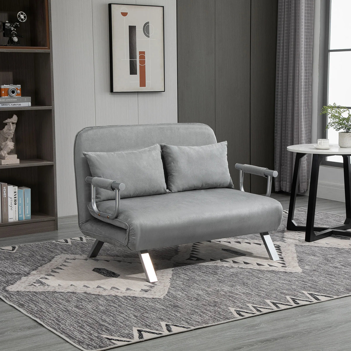 Šviesiai pilka sofa-lova modernaus interjero kambaryje su knygų lentyna