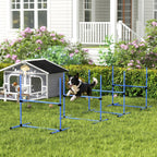 Šuo peršoka per mėlyną agility kliūtį žolėje prie šuns namelio