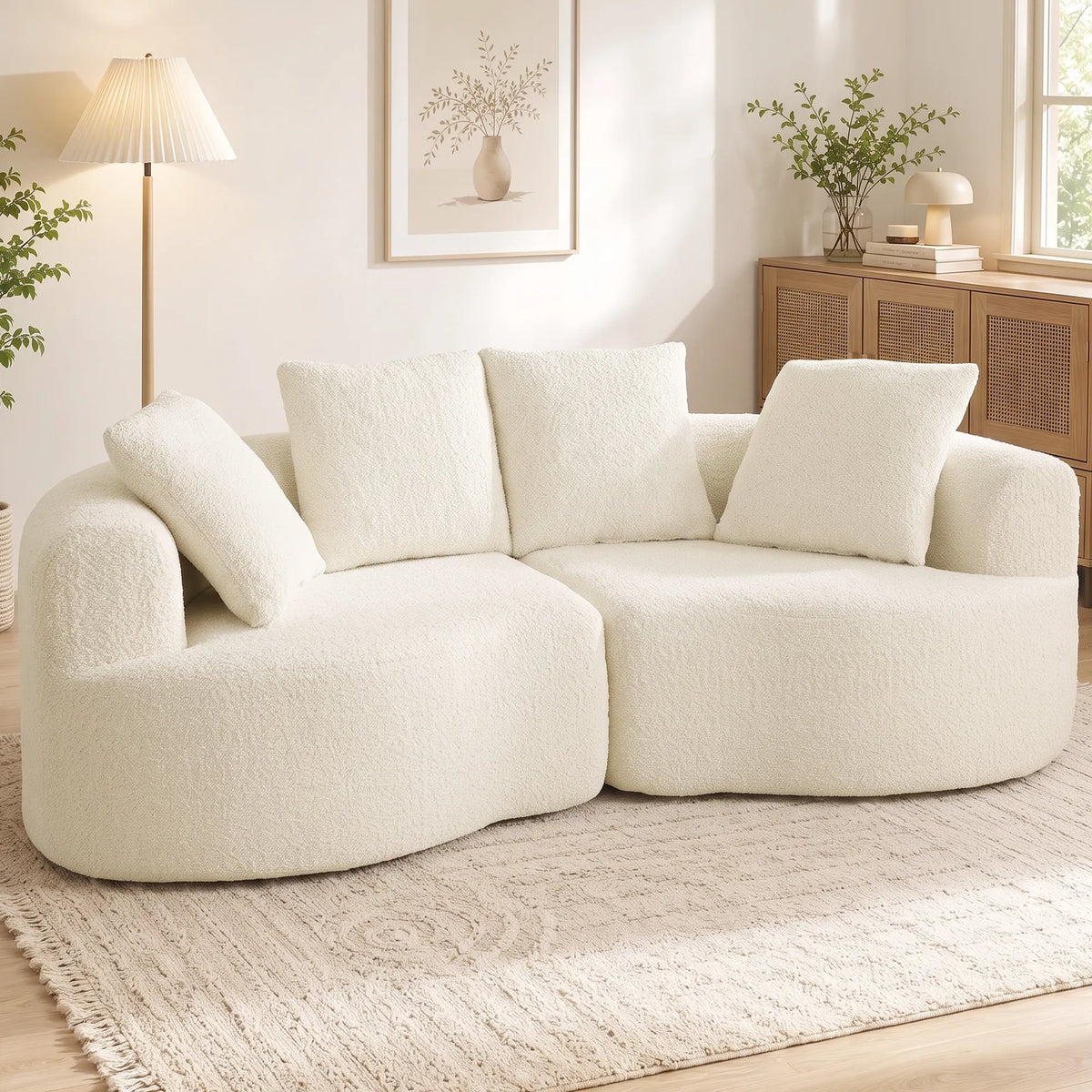 Kreminės spalvos sofa jaukioje svetainėje šalia toršero ir komodos