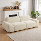 Kreminė sofa jaukiame svetainės kampe prie židinio ir augalo