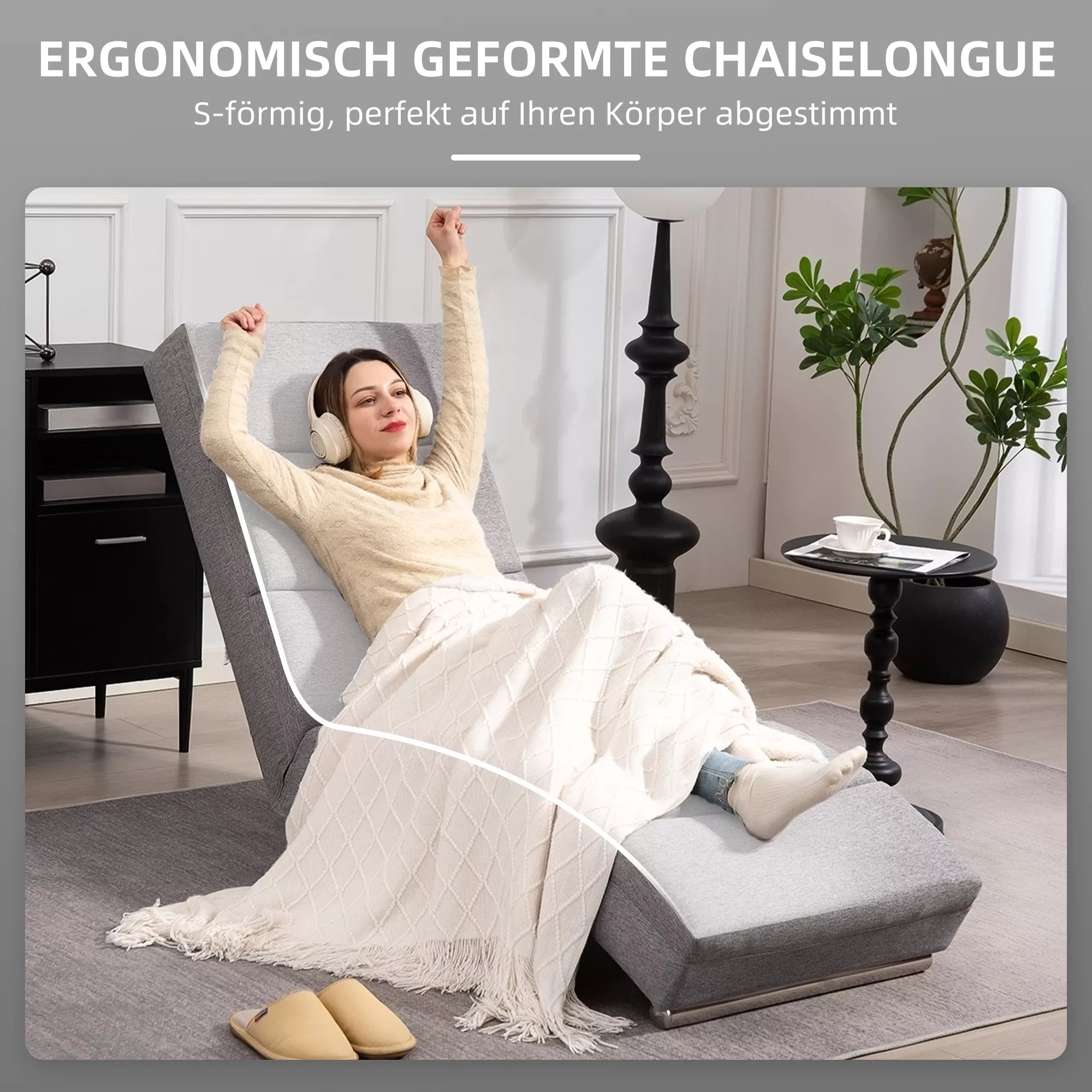 Moteris guli ant pilko chaiselongue fotelžio su ausinėmis ir nešiojamu kompiuteriu