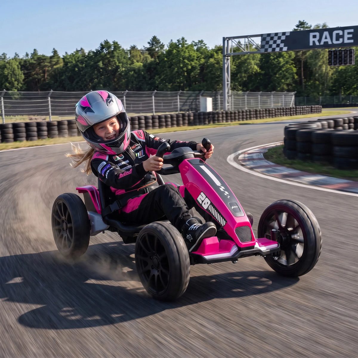Mergaitė su šalmu važiuoja gokartu po užrašu RACE tarp padangų atitvarų