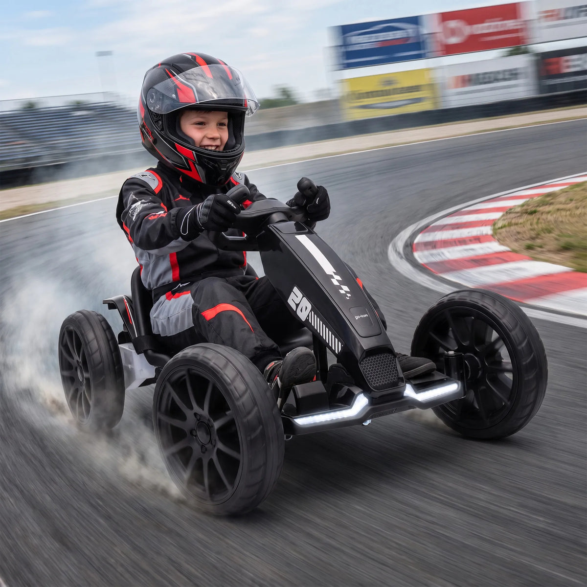 Dūmų debesyje slystantis gokartas su vairuojančiu berniuku trasoje