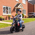 Prie plytinio namo privažiavimo berniukas su šalmu vairuoja motociklą
