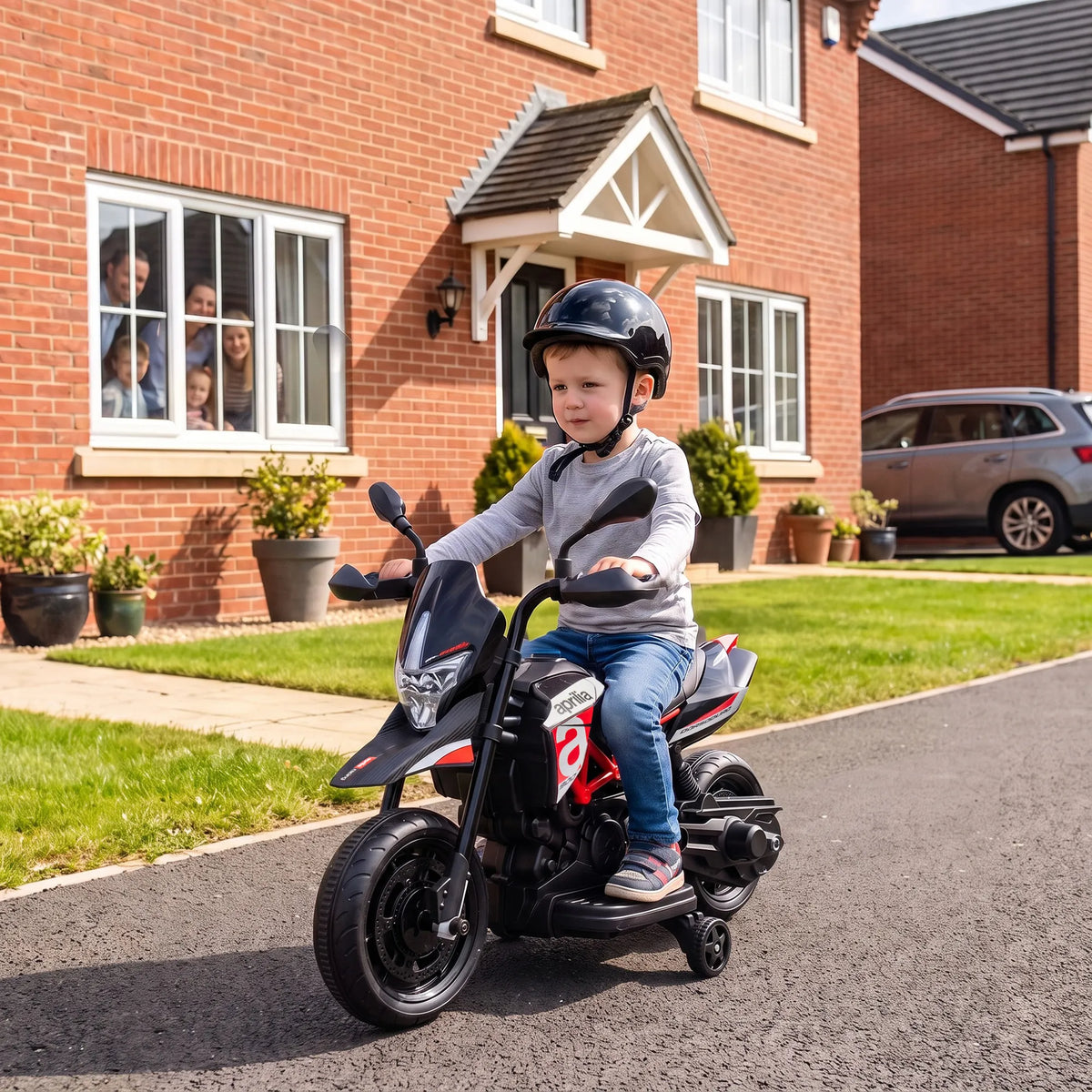 Prie plytinio namo privažiavimo berniukas su šalmu vairuoja motociklą