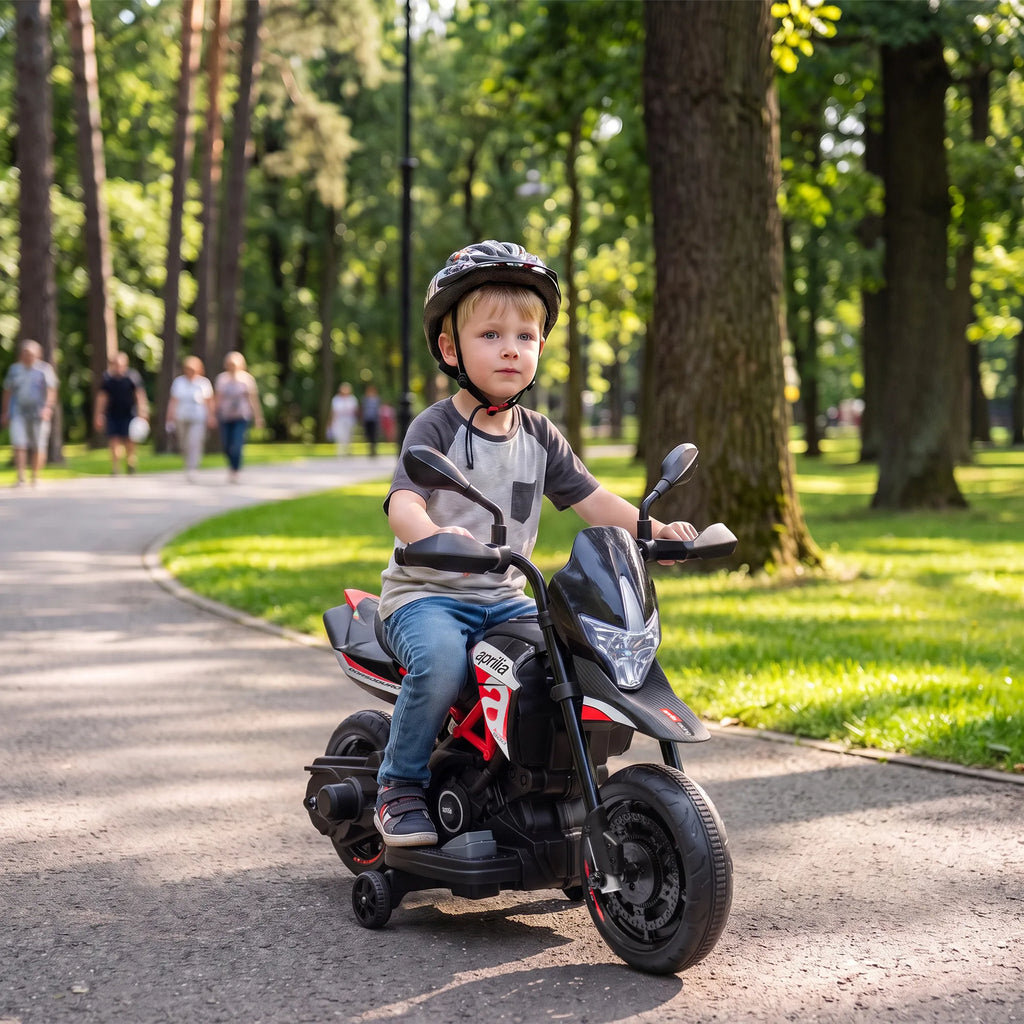 Parko takelyje berniukas su dviratininko šalmu važiuoja motociklu