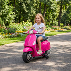 Plaukus vėjyje plaikstanti mergaitė važiuoja Vespa motociklu pro gėlynus