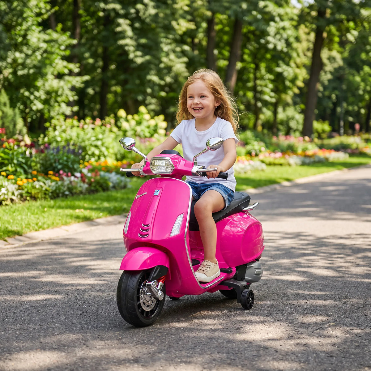 Plaukus vėjyje plaikstanti mergaitė važiuoja Vespa motociklu pro gėlynus