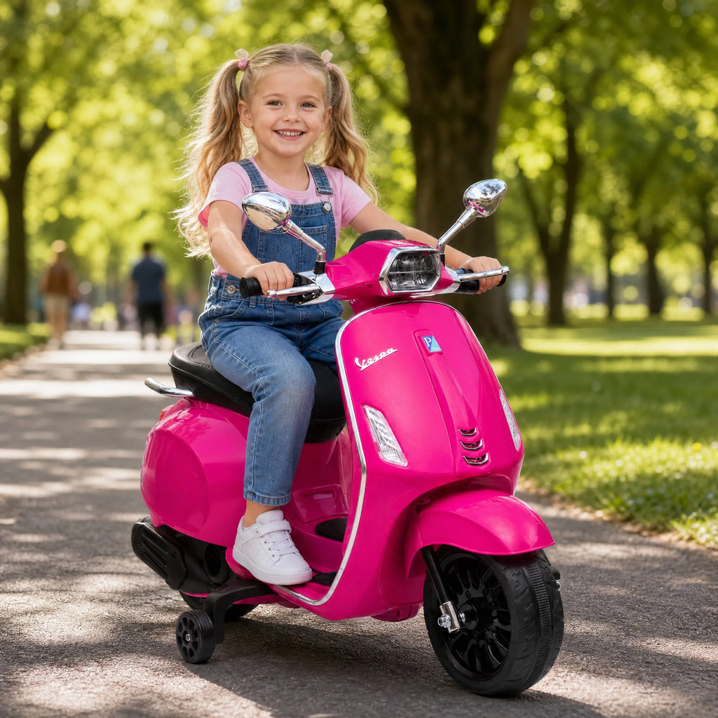 Mergaitė su kasytėmis važiuoja rožiniu Vespa motociklu pro medžius
