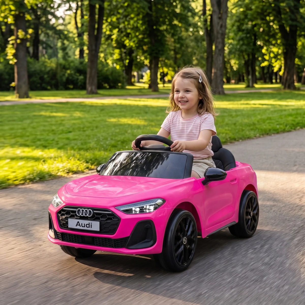 Mergaitė vairuoja rožinį vaikišką elektromobilį parko alėjoje