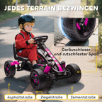 Šalmą dėvintis vaikas raudonu kombinezonu vairuoja rožinį gokartą trinkelių taku