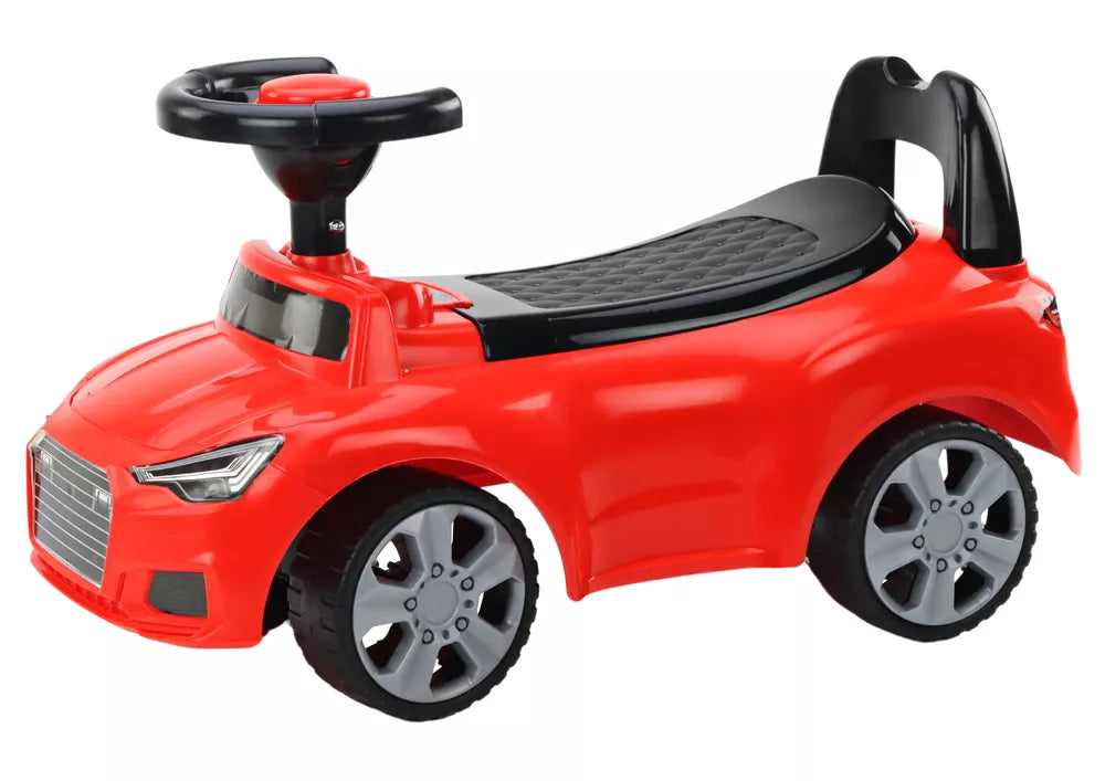 Raudonas vaikiškas stumiamas automobilis, fotografuotas iš šono